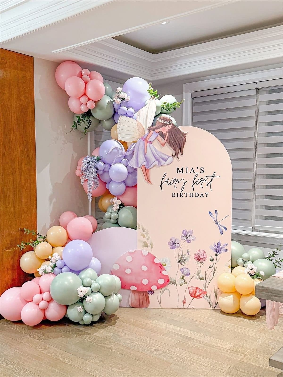 Jovira balloon arch in blush, sky blue, and sunshine tones framing a draped celebration backdrop